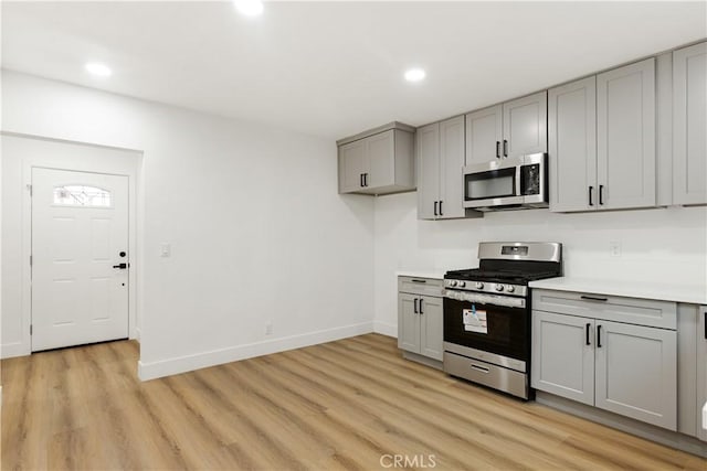 kitchen with gray cabinetry, stainless steel appliances, and light hardwood / wood-style flooring