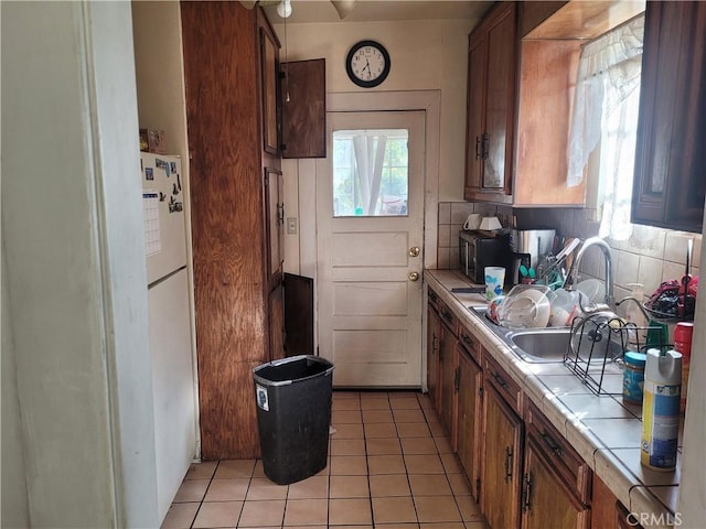 kitchen featuring light tile patterned floors, tile countertops, decorative backsplash, and a wealth of natural light