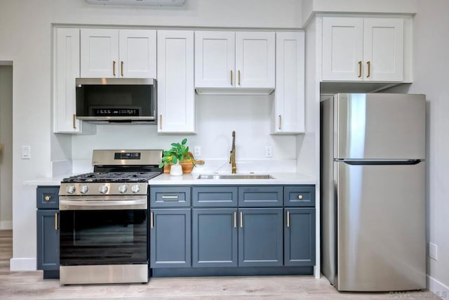 kitchen featuring appliances with stainless steel finishes, white cabinetry, light hardwood / wood-style floors, sink, and blue cabinets