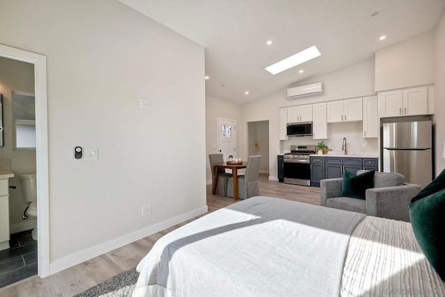 bedroom featuring vaulted ceiling with skylight, connected bathroom, sink, stainless steel fridge, and a wall mounted air conditioner