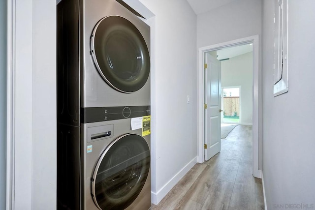 washroom with stacked washer / dryer and light hardwood / wood-style flooring