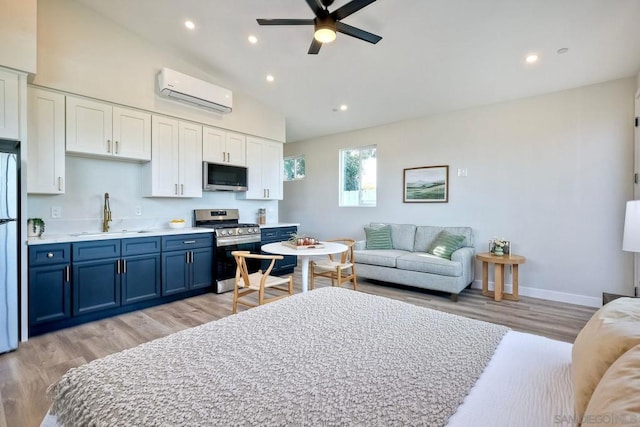 kitchen with appliances with stainless steel finishes, white cabinetry, sink, a wall mounted AC, and blue cabinets