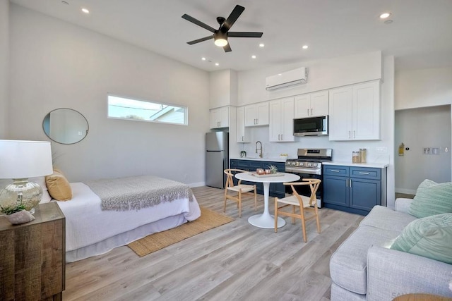 bedroom featuring light wood-type flooring, ceiling fan, stainless steel fridge, and an AC wall unit