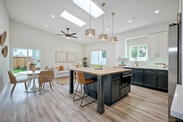 kitchen with pendant lighting, white cabinets, a center island, ceiling fan, and light hardwood / wood-style flooring