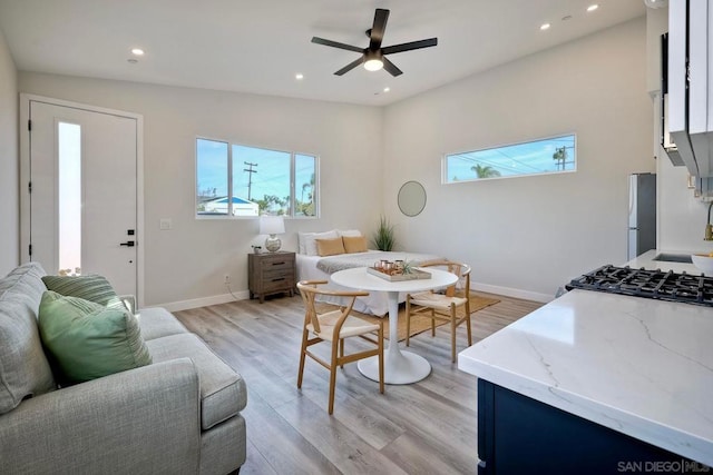 living room featuring lofted ceiling, light wood-type flooring, sink, and ceiling fan