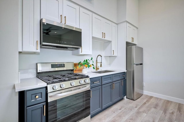 kitchen featuring blue cabinets, sink, stainless steel appliances, and white cabinetry