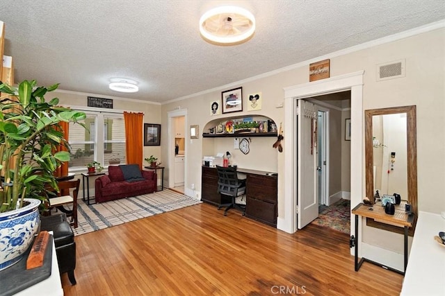 office space with built in desk, ornamental molding, hardwood / wood-style floors, and a textured ceiling