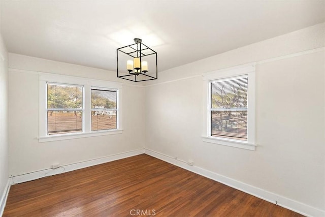 empty room featuring a notable chandelier and hardwood / wood-style flooring