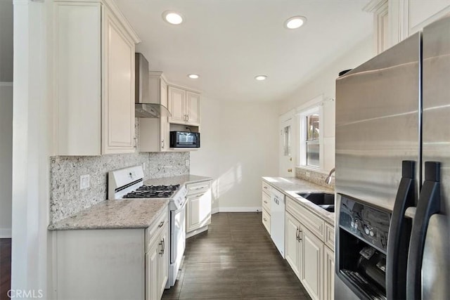 kitchen with white cabinetry, sink, light stone counters, white appliances, and wall chimney exhaust hood