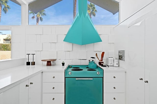 kitchen with stove, white cabinetry, and island range hood