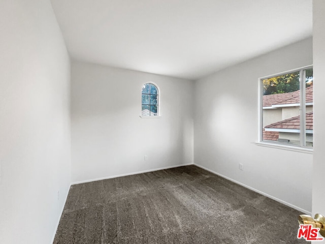 unfurnished room with dark colored carpet