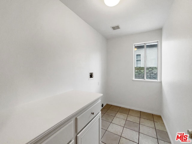 laundry area with light tile patterned flooring, washer hookup, and cabinets