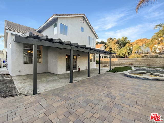 rear view of property featuring an in ground hot tub and a patio