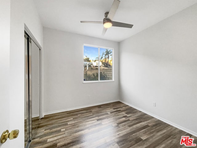 unfurnished bedroom with ceiling fan, dark wood-type flooring, and a closet