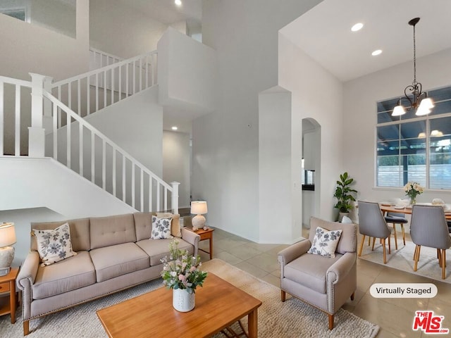 tiled living room featuring a high ceiling and an inviting chandelier