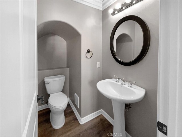 bathroom with hardwood / wood-style floors, toilet, and ornamental molding