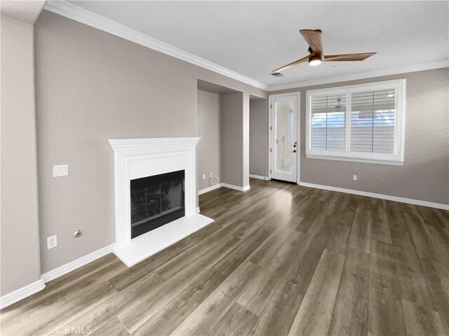 unfurnished living room with ceiling fan, dark wood-type flooring, and crown molding