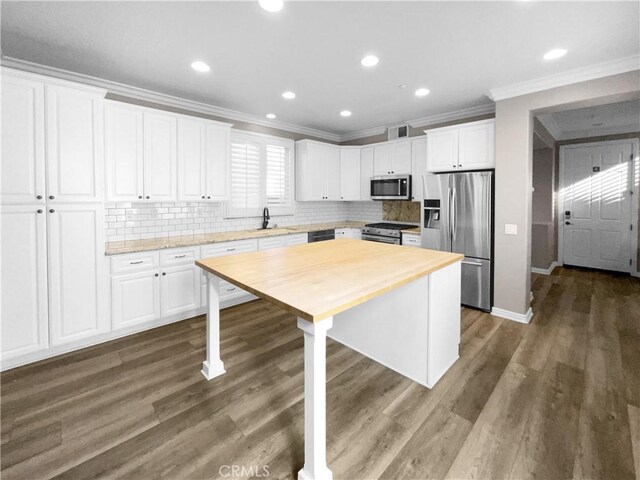 kitchen with a center island, dark wood-type flooring, white cabinetry, stainless steel appliances, and crown molding