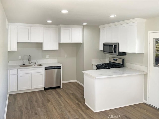 kitchen with sink, dark wood-type flooring, light stone countertops, appliances with stainless steel finishes, and white cabinets