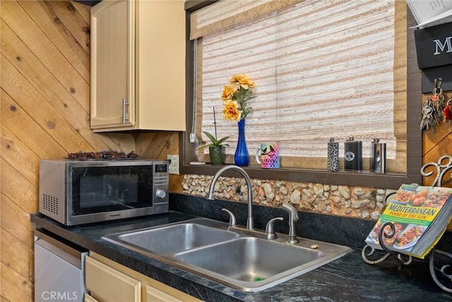 kitchen featuring sink, cream cabinets, and wooden walls