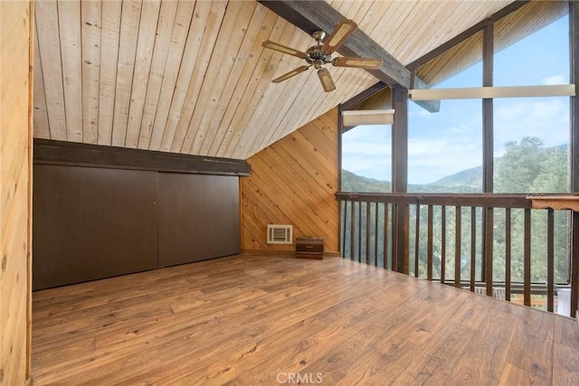 additional living space with ceiling fan, lofted ceiling with beams, a mountain view, hardwood / wood-style flooring, and wooden ceiling