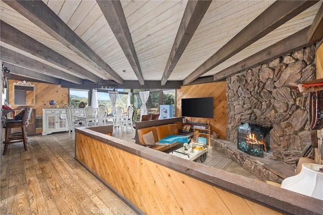 living room featuring a fireplace, hardwood / wood-style floors, wooden walls, and beamed ceiling