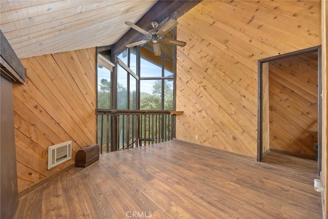 additional living space with wood walls, ceiling fan, wood-type flooring, and vaulted ceiling with beams