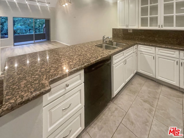 kitchen featuring black dishwasher, white cabinetry, dark stone counters, and sink