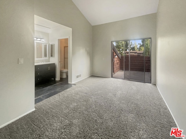 carpeted empty room with high vaulted ceiling