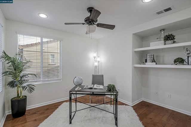 office space with built in shelves, ceiling fan, and dark hardwood / wood-style flooring