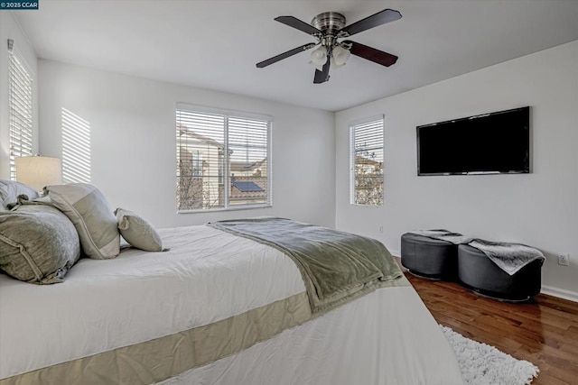 bedroom featuring hardwood / wood-style floors, ceiling fan, and multiple windows