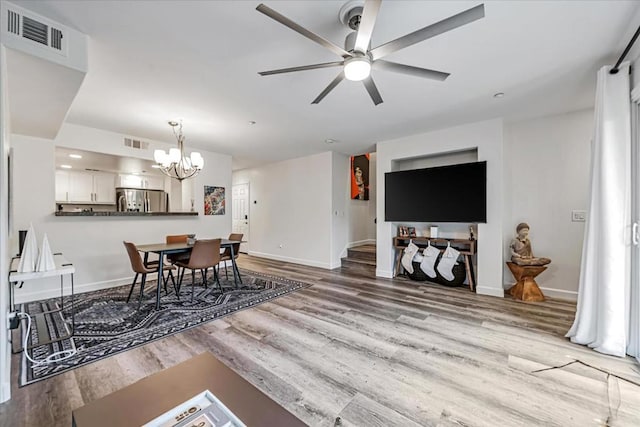 dining space with light wood-type flooring and ceiling fan with notable chandelier