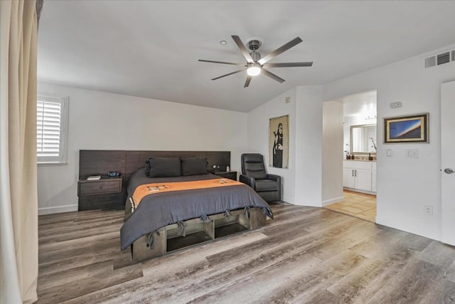 bedroom with ceiling fan, wood-type flooring, ensuite bathroom, and lofted ceiling