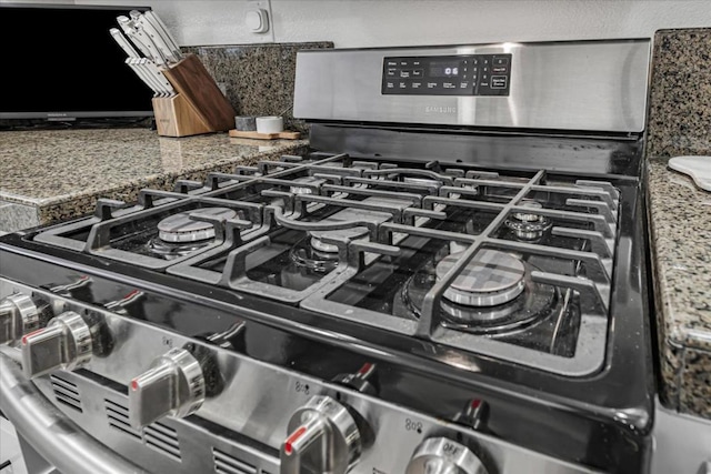 details with dark stone countertops and stainless steel range with gas cooktop