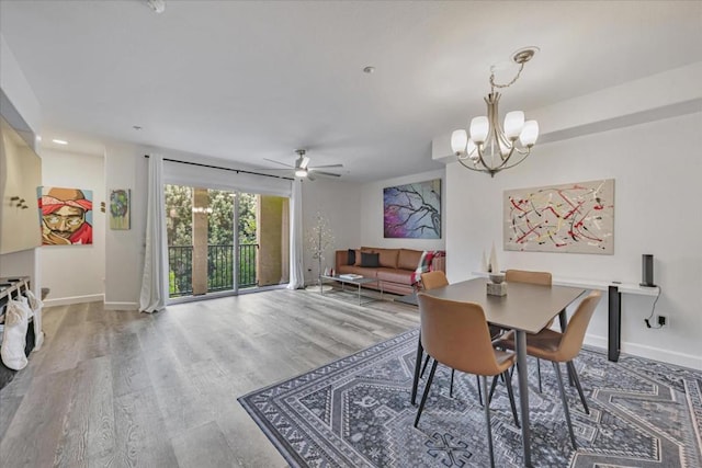 dining room with ceiling fan with notable chandelier and wood-type flooring