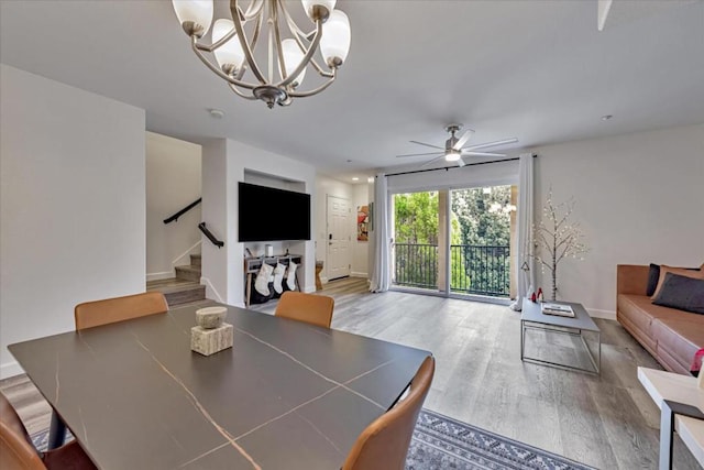 dining room featuring ceiling fan with notable chandelier and hardwood / wood-style flooring