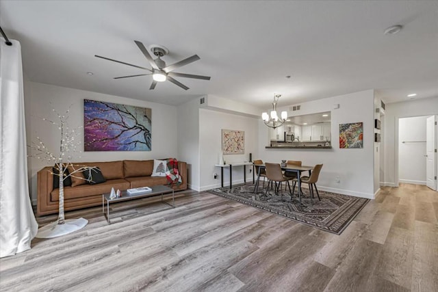 living room featuring light wood-type flooring and ceiling fan with notable chandelier