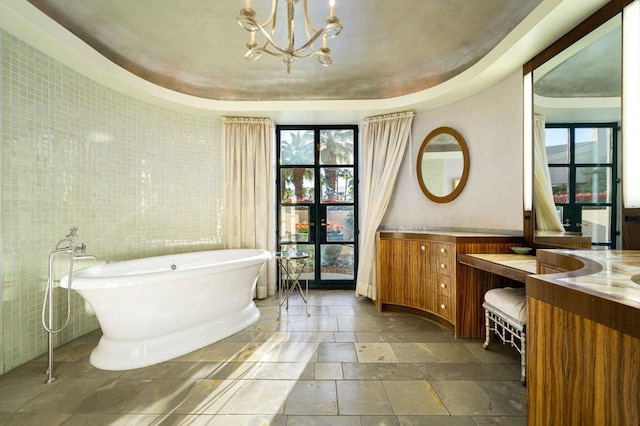 bathroom with a raised ceiling, vanity, tile walls, and a bathing tub