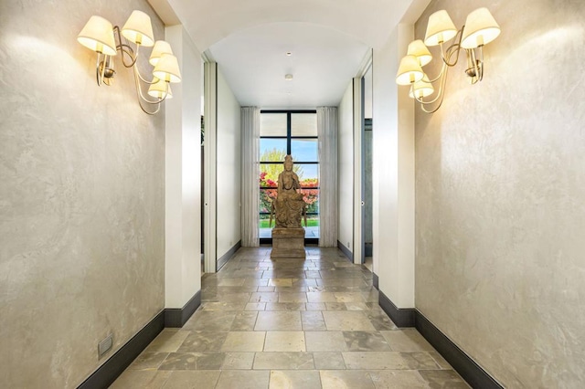 corridor featuring expansive windows and a chandelier