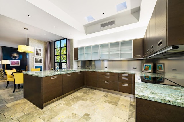 kitchen with kitchen peninsula, light stone counters, and dark brown cabinetry