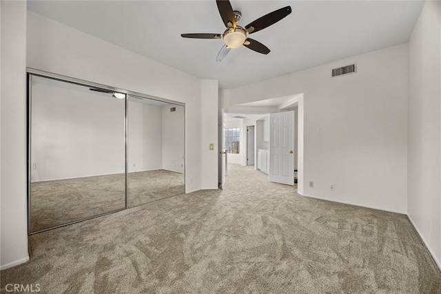 unfurnished bedroom with ceiling fan, a closet, and light carpet