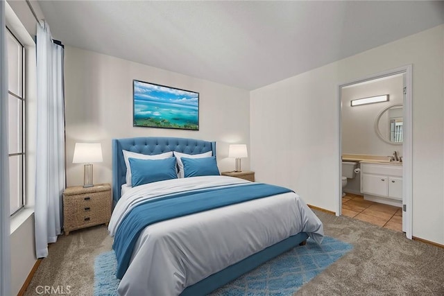 bedroom featuring sink, ensuite bathroom, and light carpet