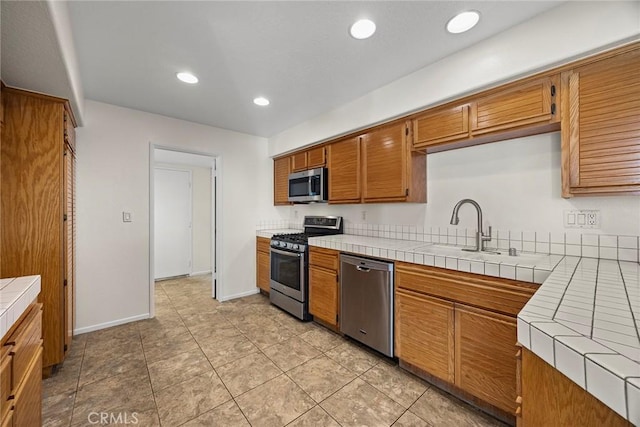 kitchen featuring light tile patterned floors, sink, appliances with stainless steel finishes, and tile countertops