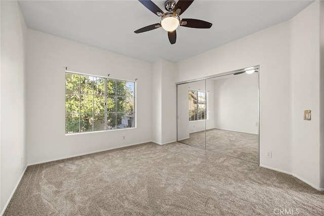 unfurnished bedroom with a closet, light colored carpet, and ceiling fan