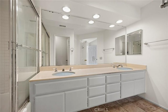 bathroom featuring tile patterned flooring, enclosed tub / shower combo, and vanity