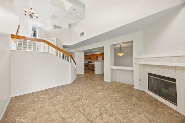 unfurnished living room with a fireplace, a high ceiling, and a notable chandelier