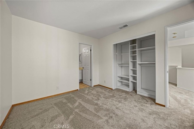 unfurnished bedroom featuring light colored carpet, connected bathroom, and a closet