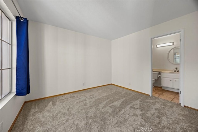 unfurnished bedroom featuring sink, light carpet, and ensuite bath