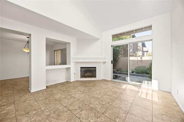 unfurnished living room with vaulted ceiling, tile patterned floors, and a tiled fireplace