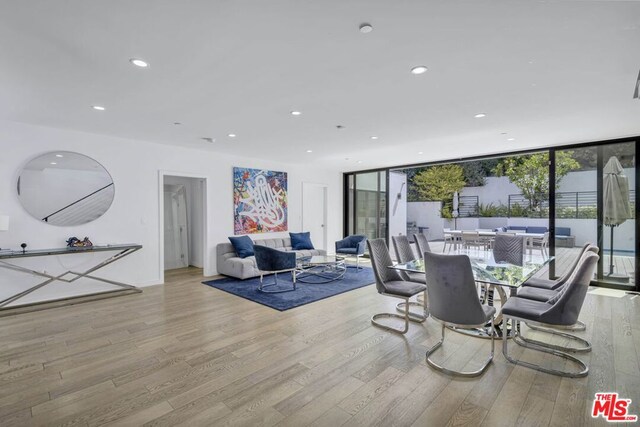 dining space with expansive windows, light wood-type flooring, and plenty of natural light